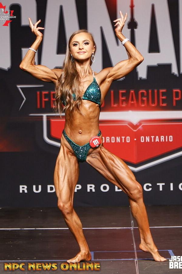 Magda Banas competing on stage, body transformation coach at Hammer Fitness Toronto